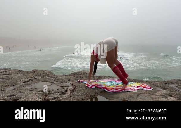Woman folding into standing balance on rocky ledge overlooking foggy ...