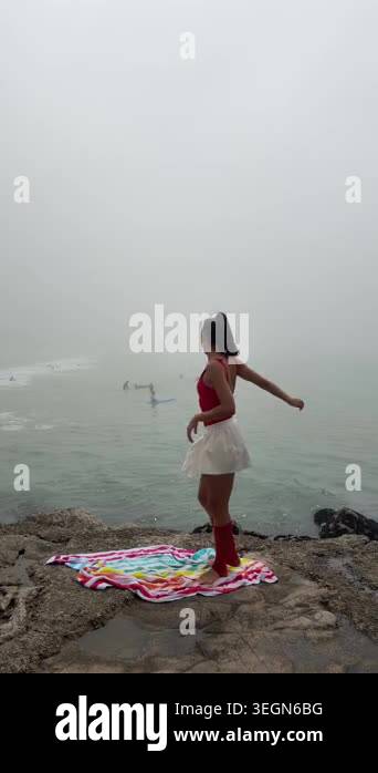 Woman improvising dance on foggy cliff towel, expressive arms and turns ...