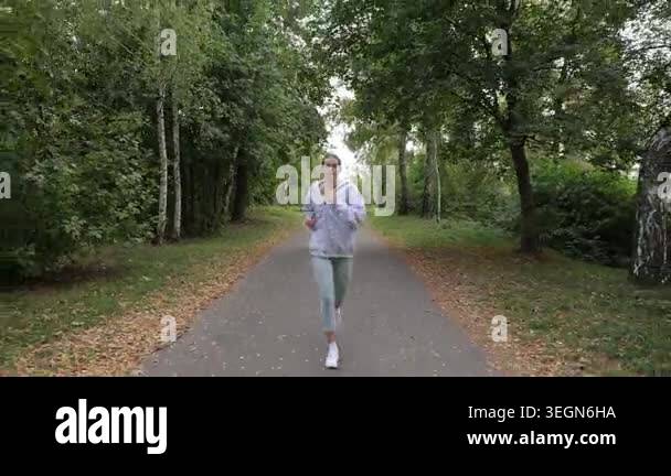 Determined young woman with glasses running towards the camera on a ...