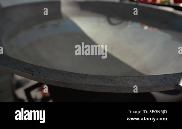 Metal cooking pan filled with clear water reflects sunlight, placed on ...
