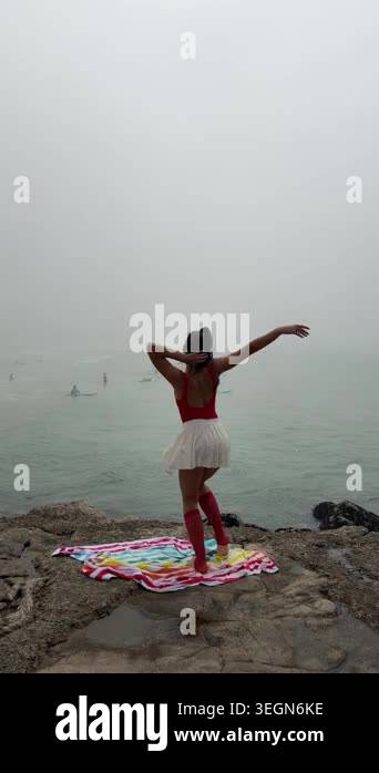 Woman reaching sideways on foggy cliff towel, graceful side stretch ...