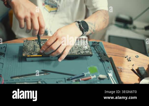 An individual works on a computer graphics card, using tools and ...