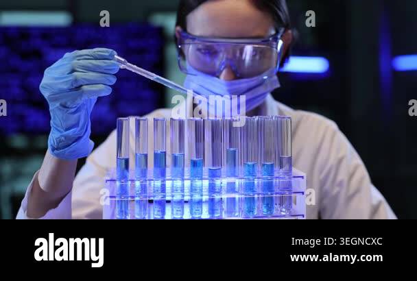 Woman scientist adds clear liquid to test tubes in lab. Gloved hand ...