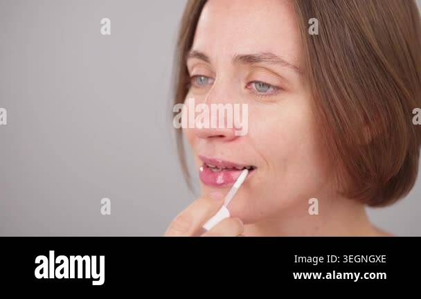 Close-up beauty portrait, happy brunette woman applying transparent lip ...