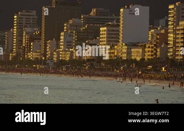 Golden light falls on a vibrant beach, city buildings, ocean waves ...