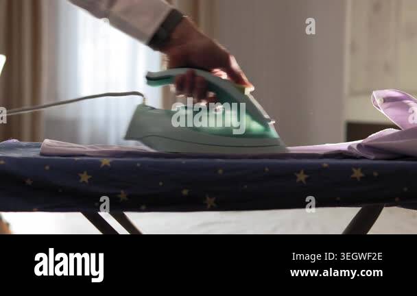 In the living room, a pink shirt lying on an ironing board. Man in his ...