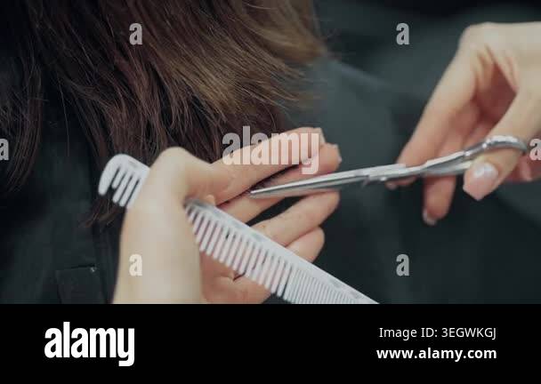 Closeup of professional hairdresser cutting client hair with scissors ...