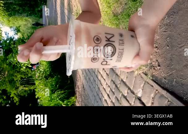 Close-up of a hand holding a plastic cup of bubble tea, tapioca balls ...