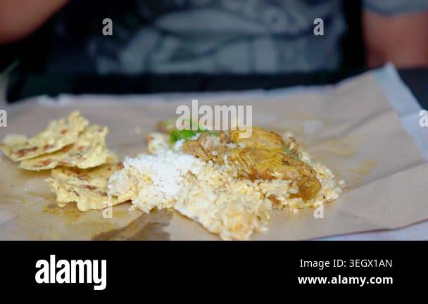 Indonesian eating rice and curry chicken with rempeyek (crackers with ...