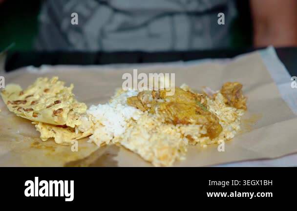 Indonesian eating rice and curry chicken with rempeyek (crackers with ...