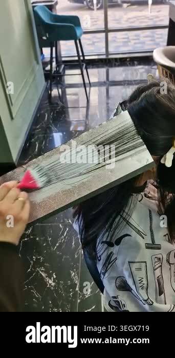 Close-up of hair lightening process. Hair strands placed on foil with ...