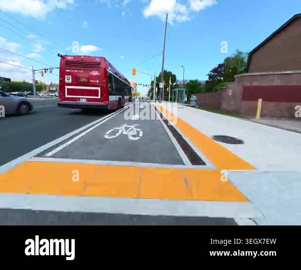 Cyclist following bus in protected bike lane with tactile strip ...