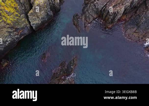 The scene shows a rocky coastline where water flows through narrow ...