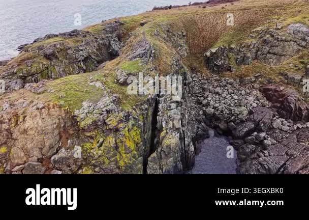 A rocky coast features cliffs rising above the ocean. Grassland covers ...