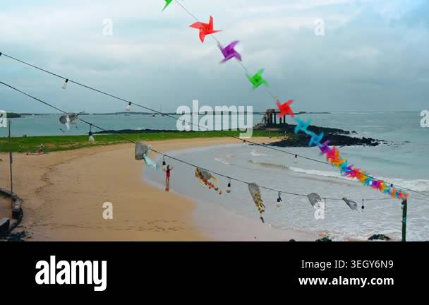 Beach decorated with light bulb and windmills garlands. Man takes video ...