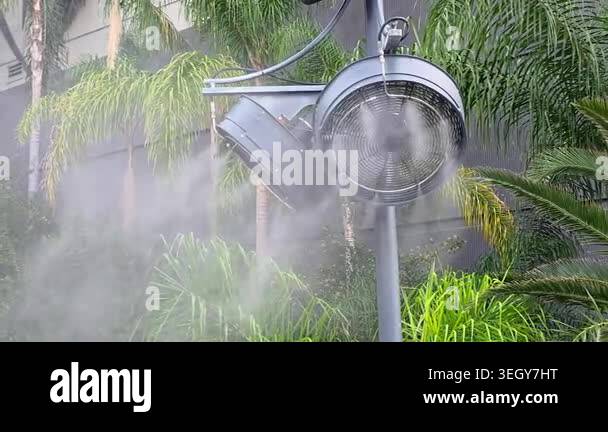 Outdoor Misting Fan Cooling Tropical Garden, close up video frame with ...