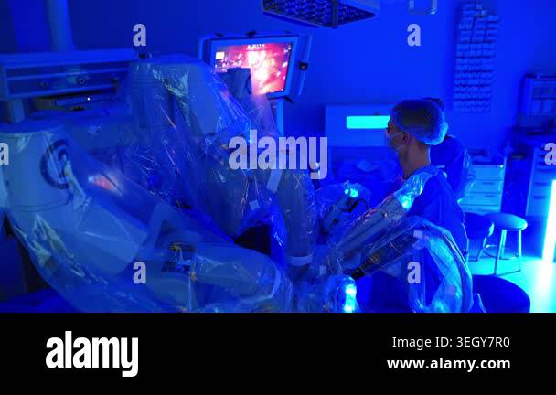 Surgery room with robotic equipment and blue light in. Medics look at ...