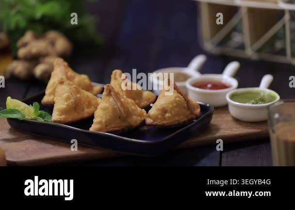 Indian samosa served with three chutney and tea as snack in closeup ...