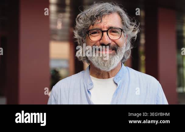 Portrait of cheerful senior man with grey hair and beard looking and ...