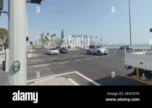 Vehicles moving at an intersection with a view of city skyline and palm ...