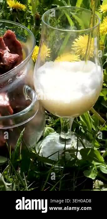 Fresh grilled pork kebab in a glass pot stands on green grass among ...