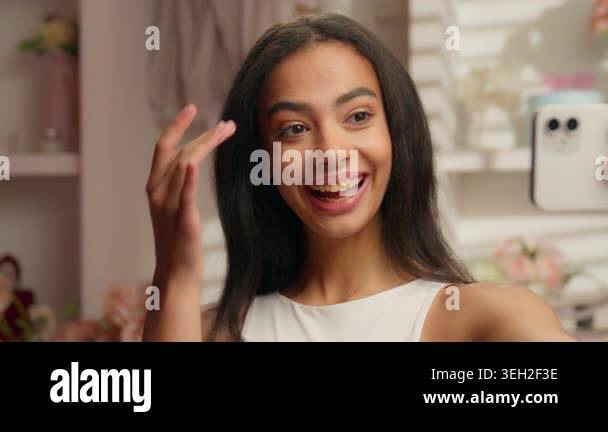 Charming American young woman holding mobile phone photographing selfie ...