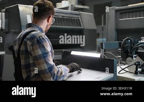 Male operator in a print plant factory working on an industrial ...