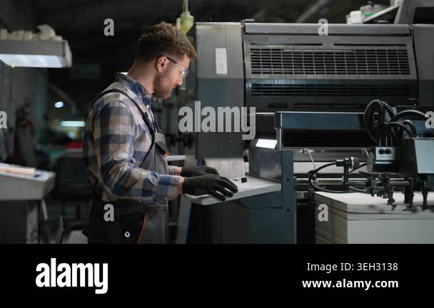 Concentrated male technician in uniform and safety glasses managing a ...
