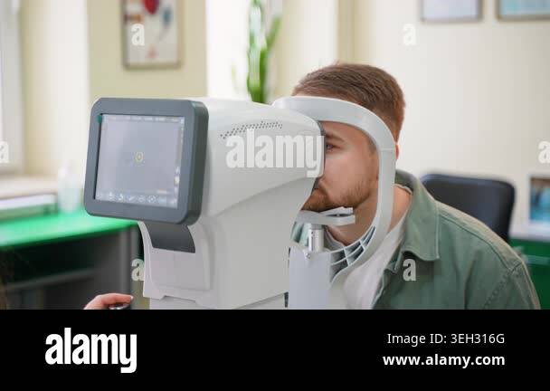Male patient getting an eye vision test with an autorefractor ...