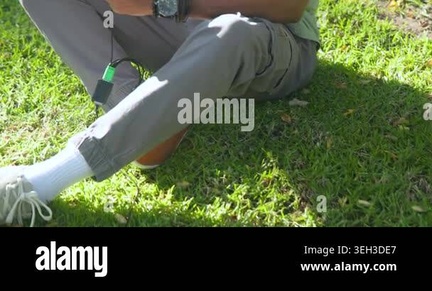Male sitting on grass adjusting solar panel connector while using ...