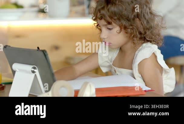 African American child leaning toward tablet taking homework notes in ...