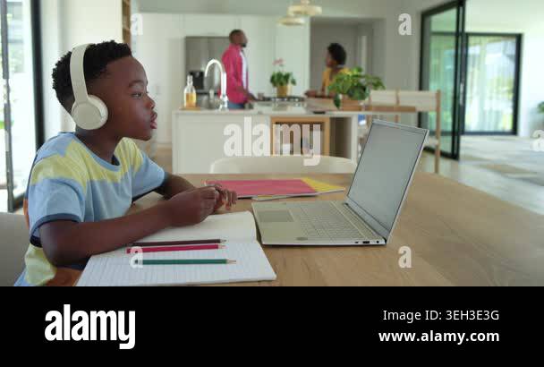 African American child boy at table, responding to laptop for class ...