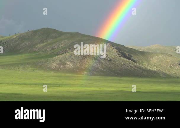 Rainbow arches across open landscape after rain, brightening broad ...