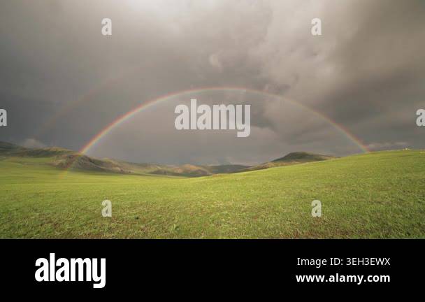 Rainbow arches across open landscape after rain, brightening broad ...