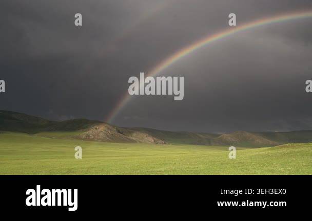 Round rainbow arcs across empty grassland under dramatic storm light ...
