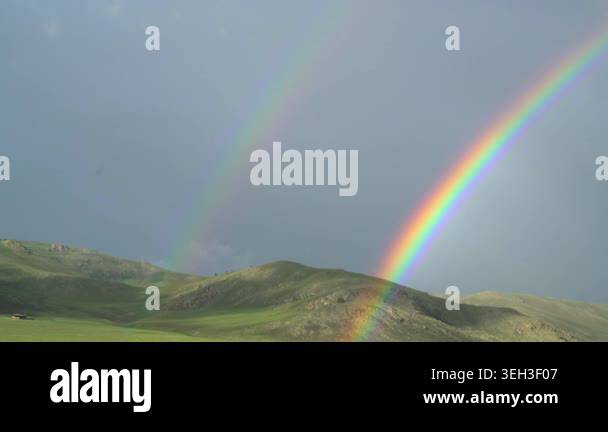 Rainbow arches across open landscape after rain, brightening broad ...