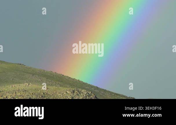 Rainbow arches across open landscape after rain, brightening broad ...