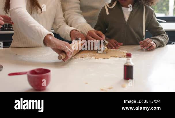 Diverse family cutting dough with cookie cutters at kitchen island ...