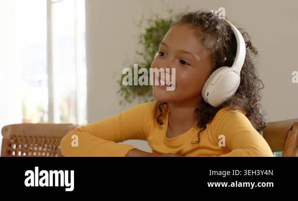 School-age girl hearing audio on wireless headphones nodding and ...