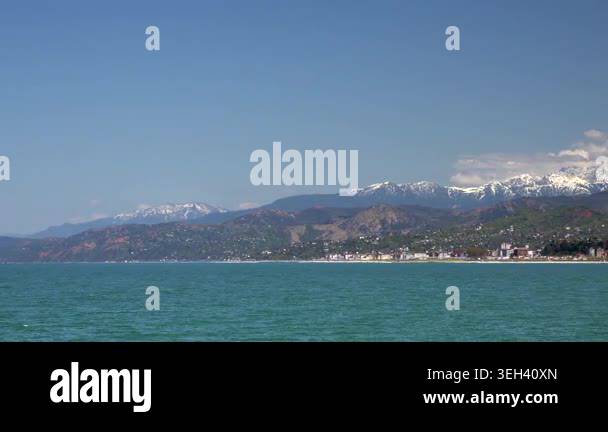 Seaside town lies between forested hills and snowy peaks, overlooking ...