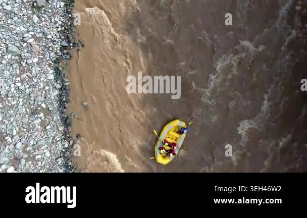 Aerial view of yellow rafting boat floating on muddy turbid river water ...