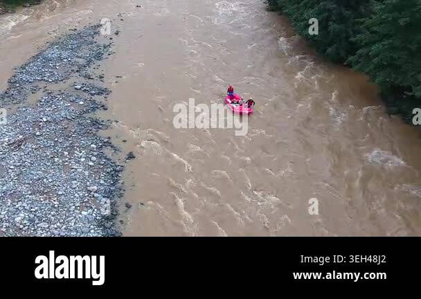 Colorful Rafting Water Aerial view of red magenta rafting boat floating on muddy turbid river ...