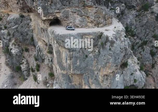 Aerial view of car driving along extremely dangerous rocky mountain ...