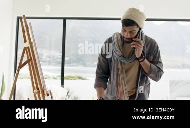 Indian artist taking smartphone call while painting on easel with ...