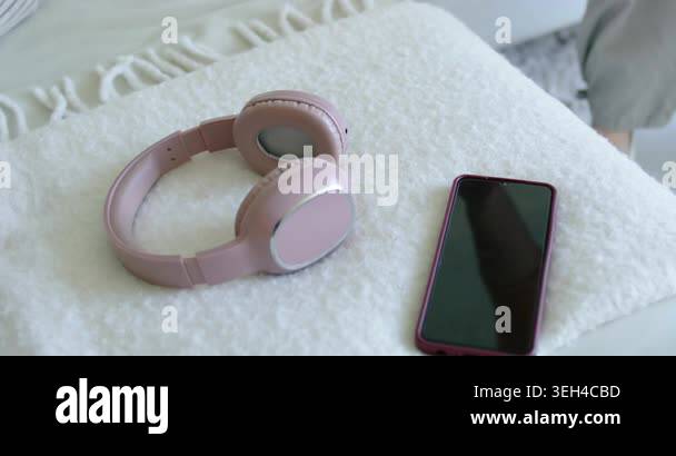 Picture of Woman right hand reaching lifting pink headphones for music from throw ...