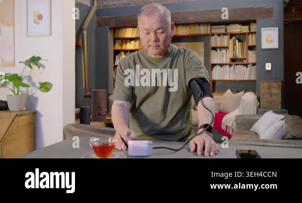 Senior Asian man pressing start on white monitor at home, monitoring ...