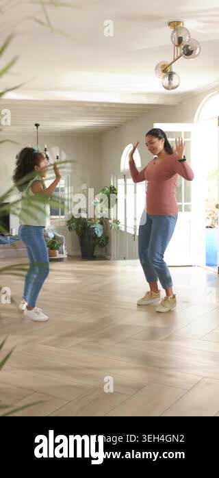 Vertical video: Female mom and daughter dancing at home near window ...