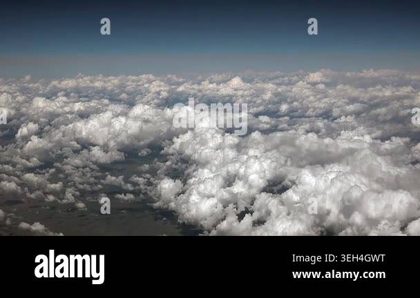 Small cotton clouds seen from plane window in bright sky during an ...