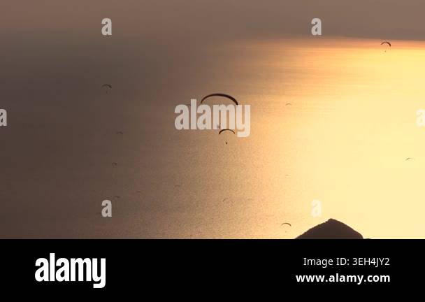Paragliders drift across sunset sky above sea and islands near Fethiye ...