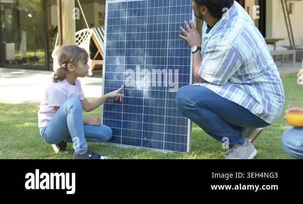 Family patio lawn holding solar panel, child pointing cells, man ...